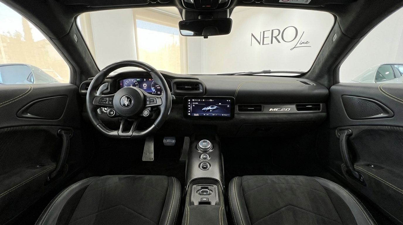 The luxurious interior of the Maserati MC20 supercar in Valencia, showcasing its steering wheel, digital dashboard, and infotainment screen.