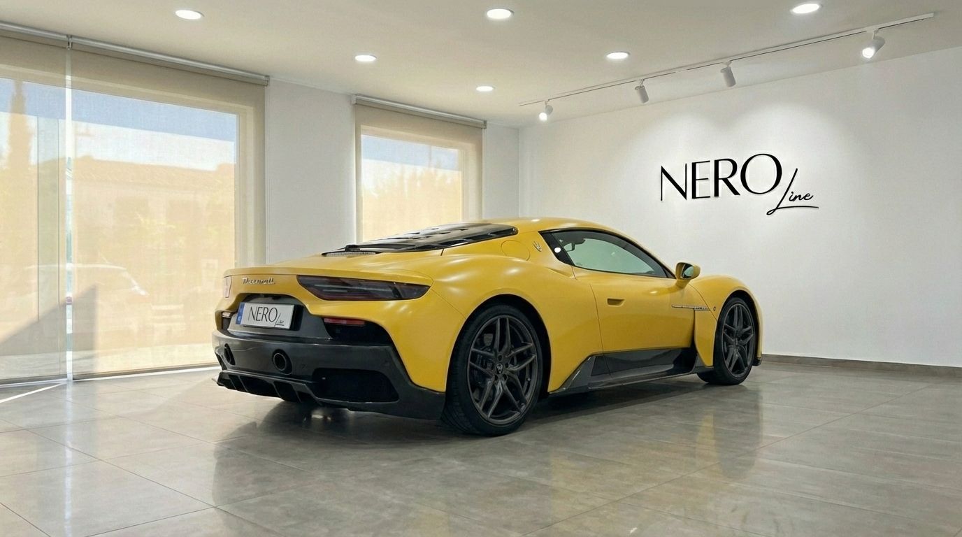 The yellow 2023 Maserati MC20 is showcased from a rear three-quarter angle in a bright Valencia showroom.