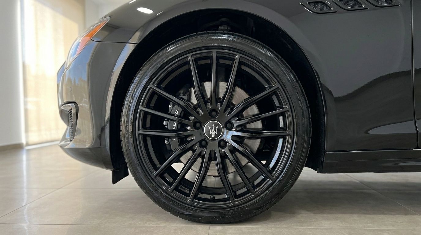 Close-up of the glossy black front wheel and fender of the Maserati Quattroporte Sq4 Nerissimo in Madrid.