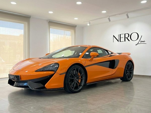 McLaren 570S Spider — Vista de showroom Madrid El McLaren 570S Spider naranja está aparcado en un concesionario, capturado desde un ángulo frontal tres cuartos en Madrid.