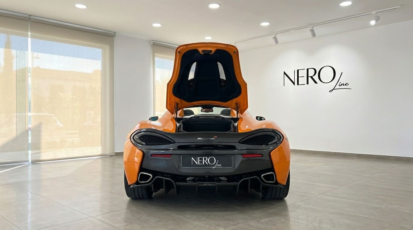 El McLaren 570S Spider naranja se muestra desde la parte trasera con el compartimento del motor abierto, estacionado en un luminoso concesionario en Madrid.