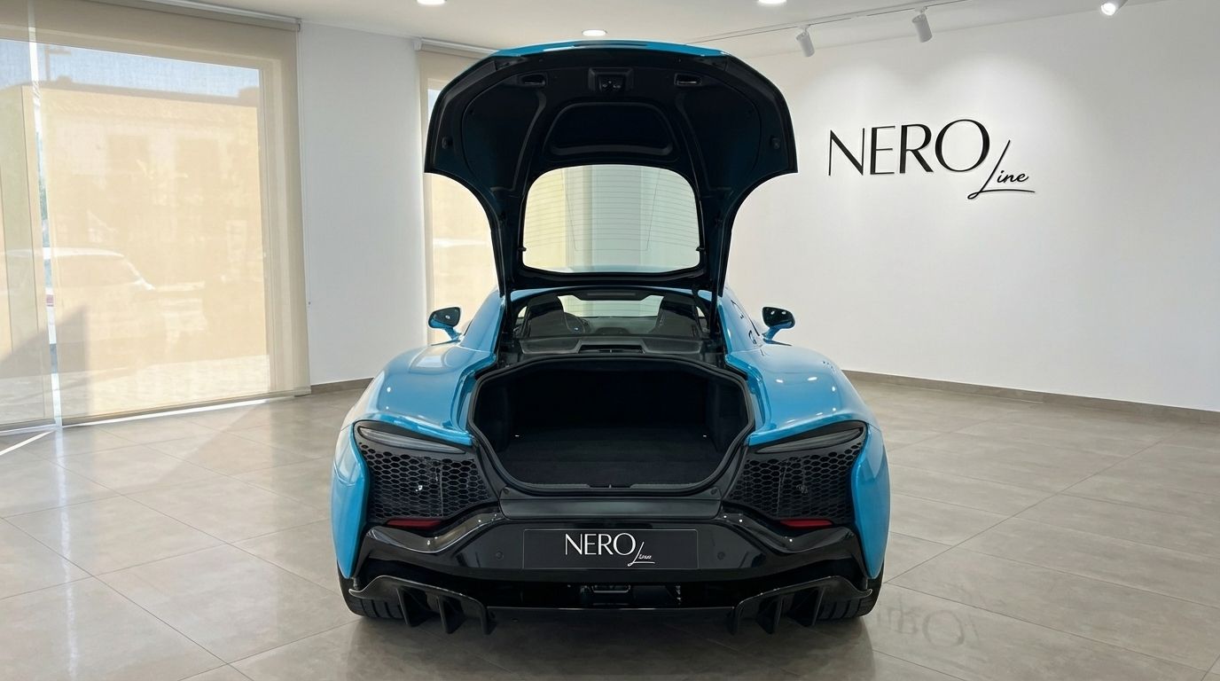 The rear view of a Tokyo Cyan McLaren Artura with its trunk open, displayed in a showroom in Marbella.
