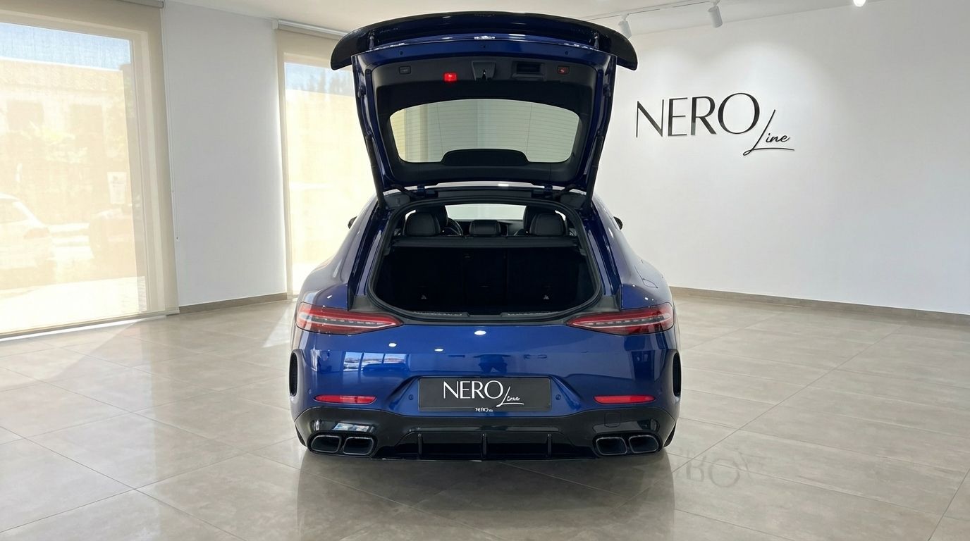 A blue Mercedes-Benz AMG GT 4-Door Coupe is seen from the rear with its trunk open in a showroom in Alicante.