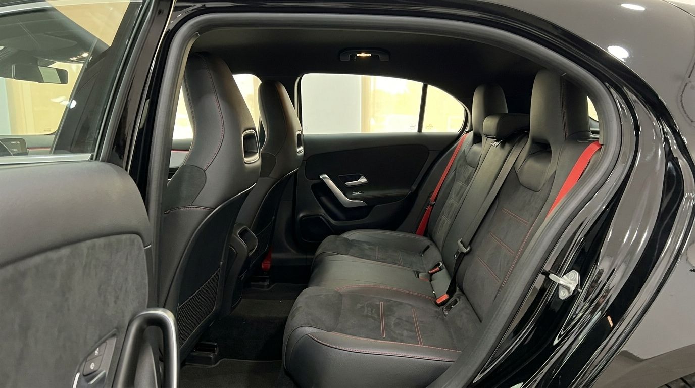 Der hintere Innenraum des Mercedes-Benz A 35 AMG 2022 in Alicante, mit schwarzen Sportsitzen mit roten Nähten und Gurten.