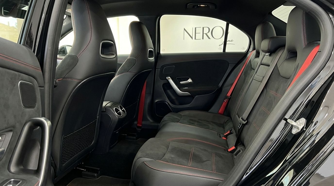 Luxurious rear interior of the Mercedes-Benz A35 AMG Limousine in Alicante, with black sport seats, red stitching and seatbelts.