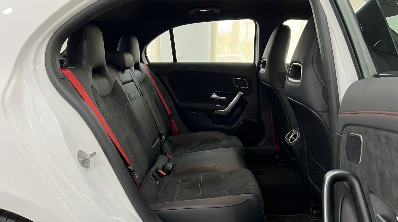 L'intérieur arrière de la Mercedes-Benz A45s AMG à Marbella, avec des sièges sport noirs, surpiqûres et ceintures rouges.