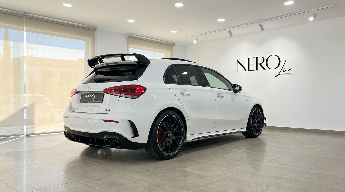El Mercedes-Benz A45s AMG blanco está estacionado en una sala de exposición, mostrando su vista trasera tres cuartos con un gran alerón y escape cuádruple en Madrid.