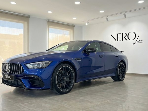 Mercedes-Benz AMG GT 4-Door Coupe — Luxury Sedan A striking blue Mercedes-Benz AMG GT 4-Door Coupe is showcased from a front three-quarter angle inside a showroom in Alicante.