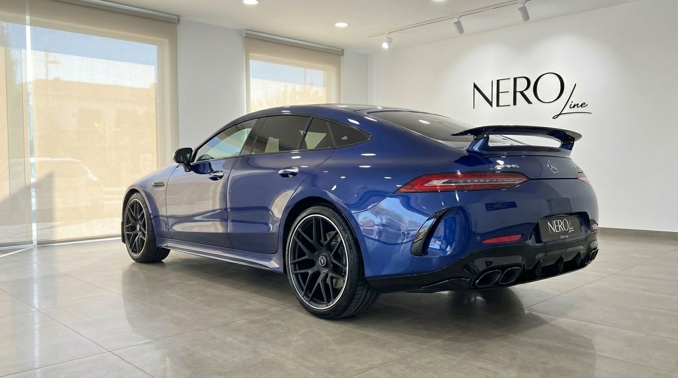 A blue 2020 Mercedes-Benz AMG GT 4-Door Coupe is parked in a showroom, showcasing its sleek rear three-quarter view in Alicante.