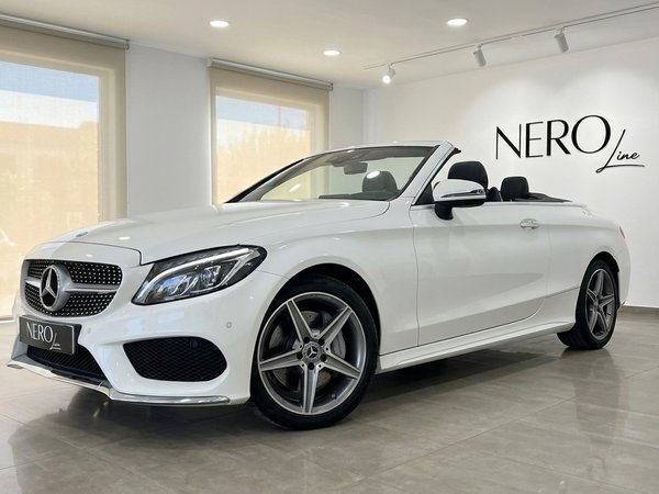 Mercedes-Benz C 200 Cabriolet — Luxury Convertible The white Mercedes-Benz C 200 Cabriolet convertible is showcased from a front three-quarter angle in a bright Alicante showroom.