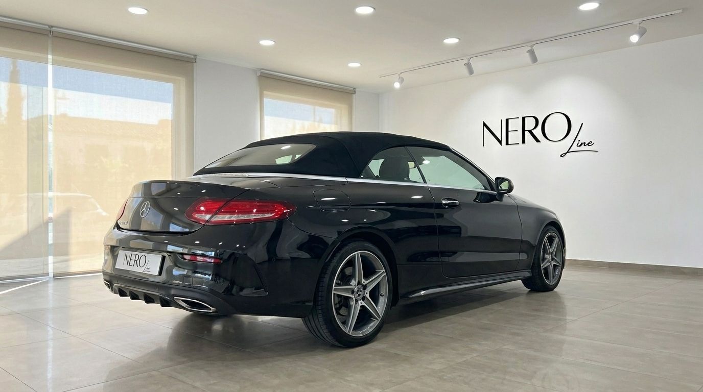 The black Mercedes-Benz C-Class Cabriolet with its soft top up, viewed from the rear three-quarter angle in a showroom in Alicante.