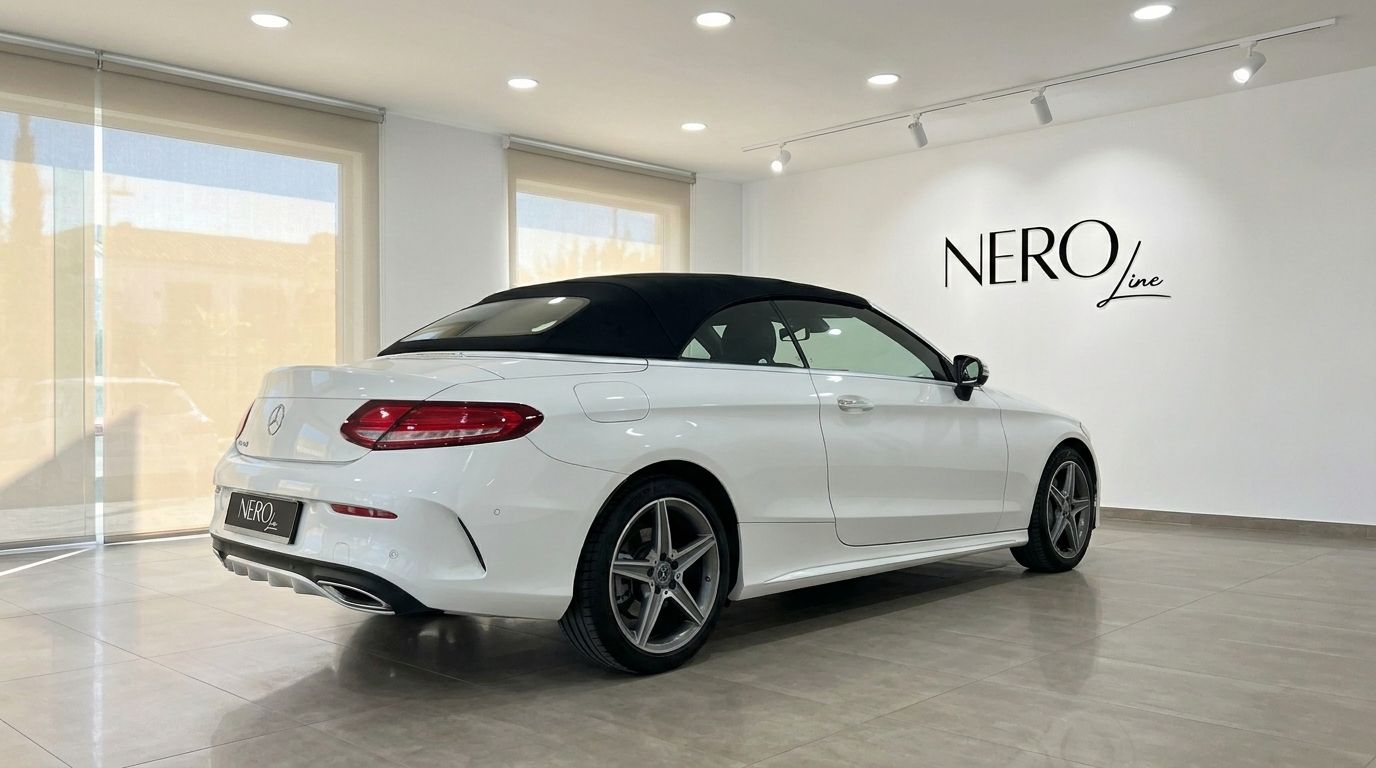 White Mercedes-Benz C 200 Cabriolet 2020 with its black soft top up, shown from the rear three-quarter in a showroom in Alicante.