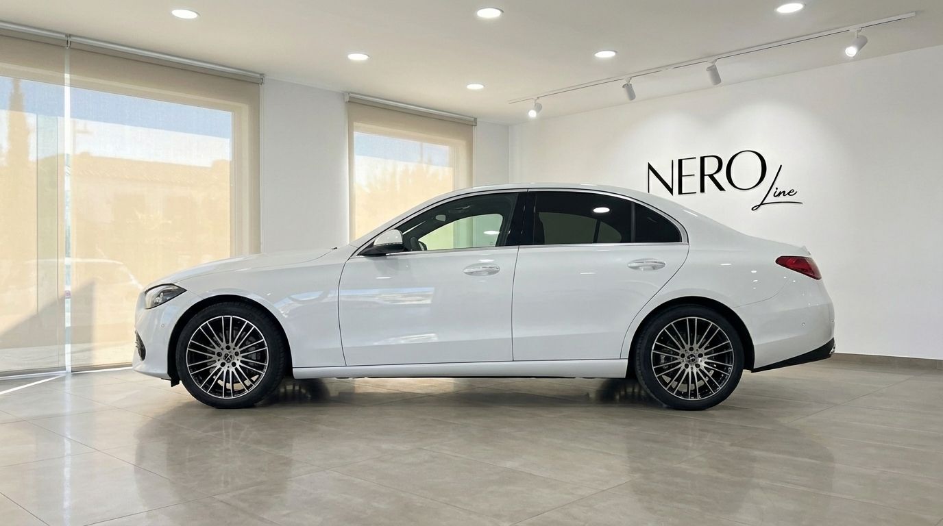 A white 2024 Mercedes-Benz C220d luxury sedan is parked in a showroom, viewed from its elegant side profile in Alicante.