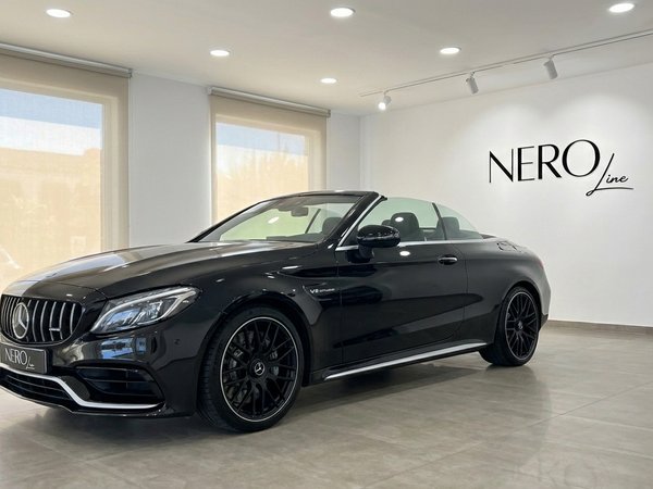 Mercedes-Benz C63 AMG — Convertible in Ibiza showroom The gloss black Mercedes-Benz C63 AMG convertible is showcased from the front three-quarter angle in a showroom in Ibiza.