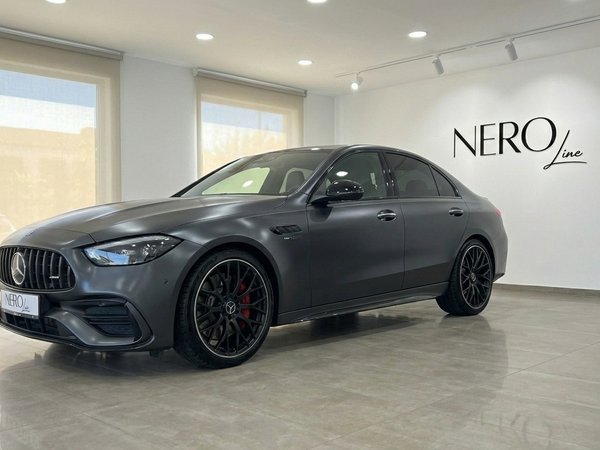 Mercedes-Benz C63 AMG — Luxury sedan in Alicante The dark metallic grey 2024 Mercedes-Benz C63 AMG luxury sedan is showcased from a front three-quarter angle in a bright Alicante showroom.