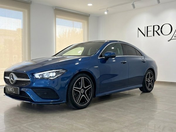Mercedes-Benz CLA — Vista frontal tres cuartos El Mercedes-Benz CLA azul de 2022 se exhibe desde un ángulo frontal tres cuartos en una luminosa sala de exposición en Mallorca.