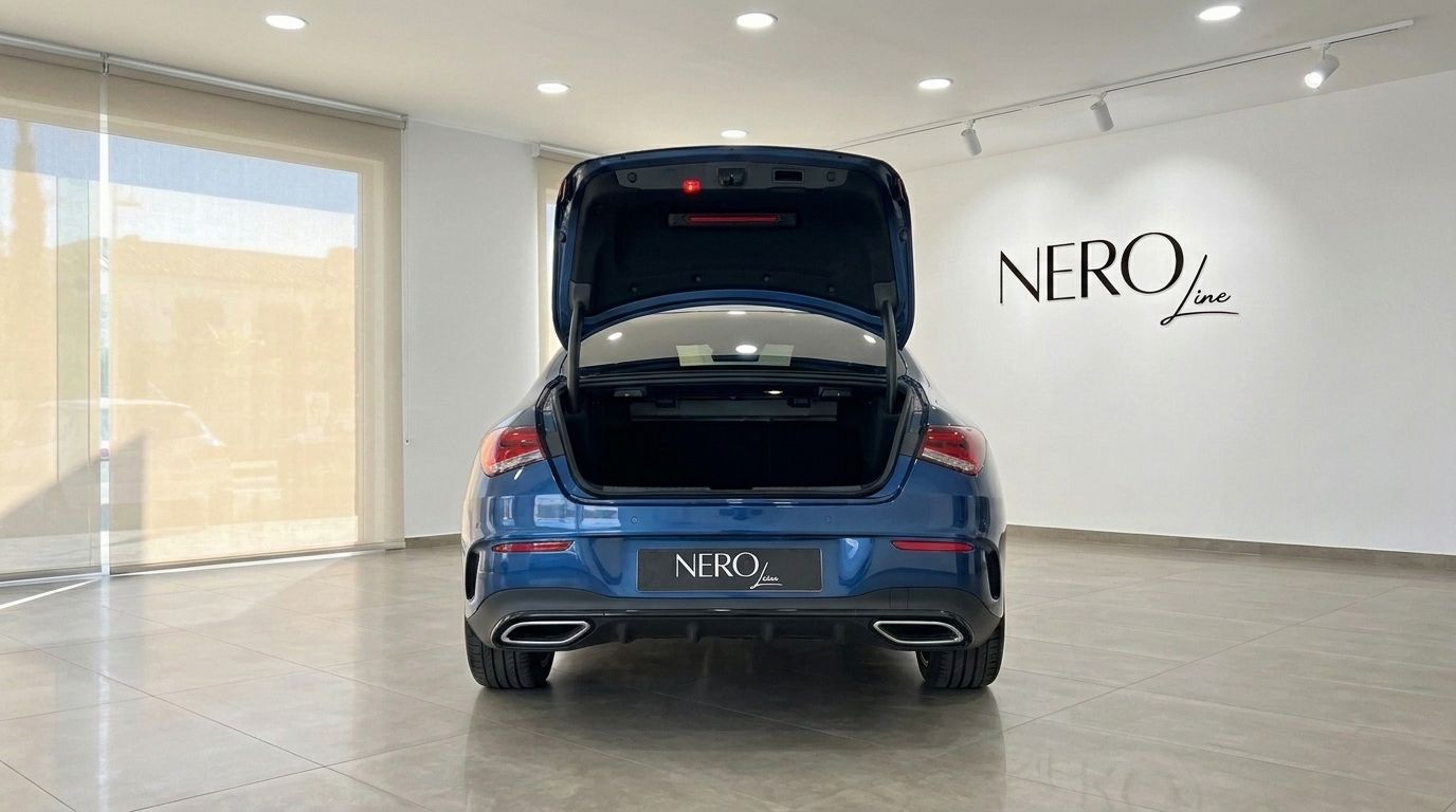 The rear view of a glossy metallic blue Mercedes-Benz CLA with its trunk open, parked in a showroom in Mallorca.