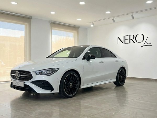 Mercedes-Benz CLA 200 — Front three-quarter view A white Mercedes-Benz CLA 200 is parked indoors, showcasing its sleek front three-quarter view in Alicante.