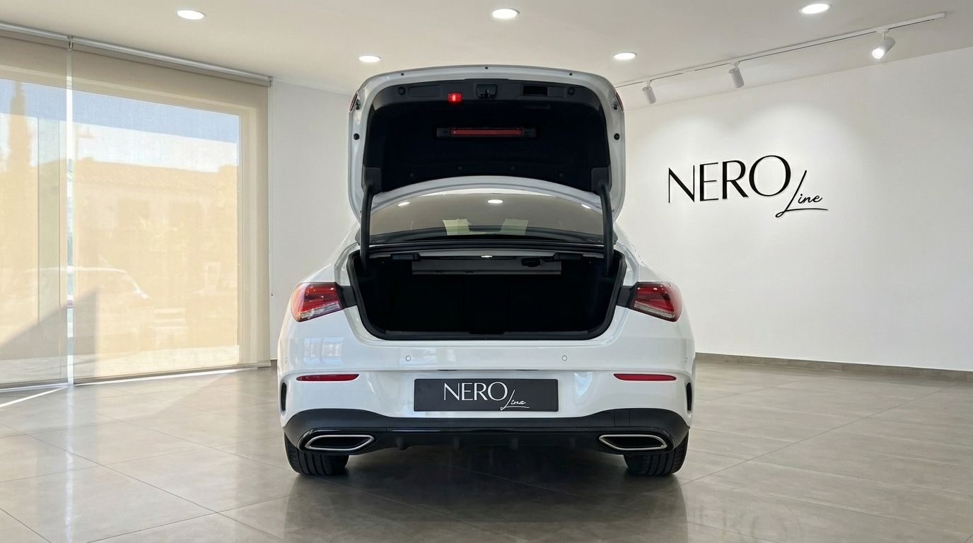 The white 2025 Mercedes-Benz CLA 200 is shown from the rear with its trunk open, revealing ample storage space in Alicante.
