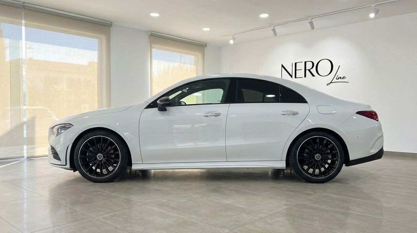 The white 2025 Mercedes-Benz CLA 200 is elegantly displayed in a side profile view inside a showroom in Alicante.