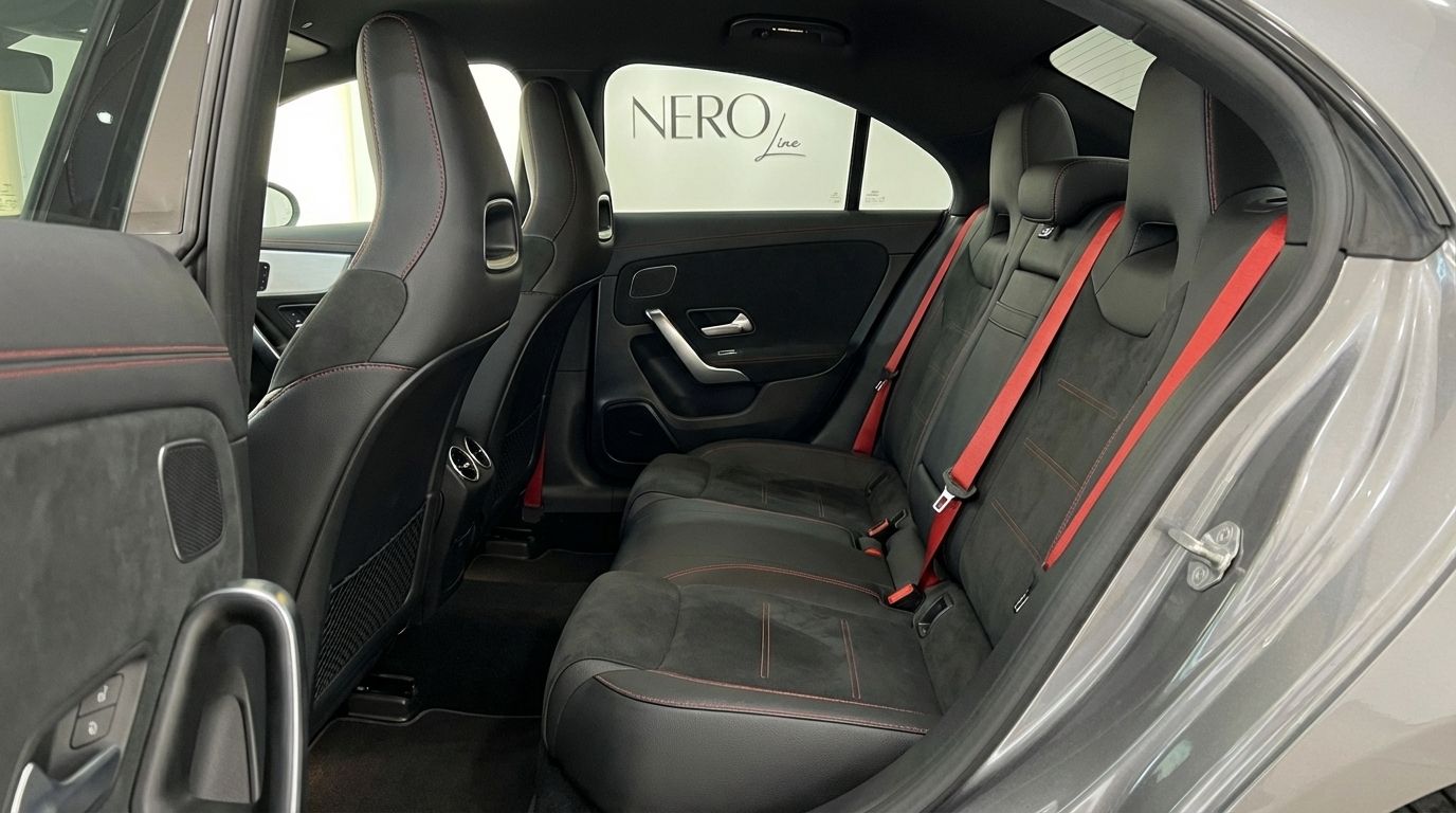 The rear interior of the Mercedes-Benz CLA 45s AMG in Alicante, featuring black leather seats with red stitching and red seatbelts.