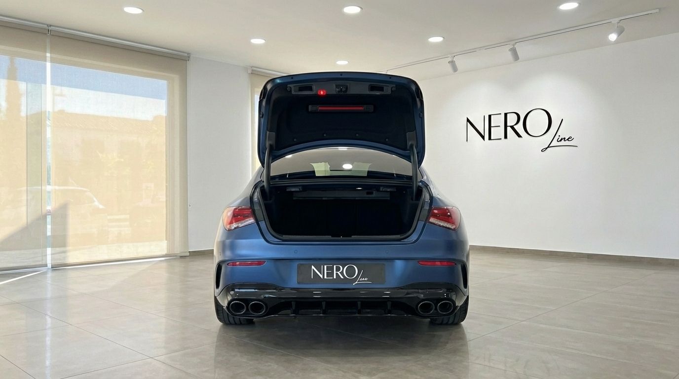 The rear view of the matte blue Mercedes-Benz CLA 45s AMG in Alicante, showcasing its open trunk and quad exhaust.