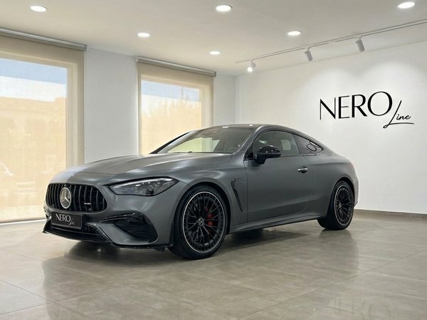Mercedes-Benz CLE 53 AMG Coupe — Showroom in Alicante A matte grey 2025 Mercedes-Benz CLE 53 AMG Coupe is parked in a bright showroom in Alicante, shown from the front three-quarter view.
