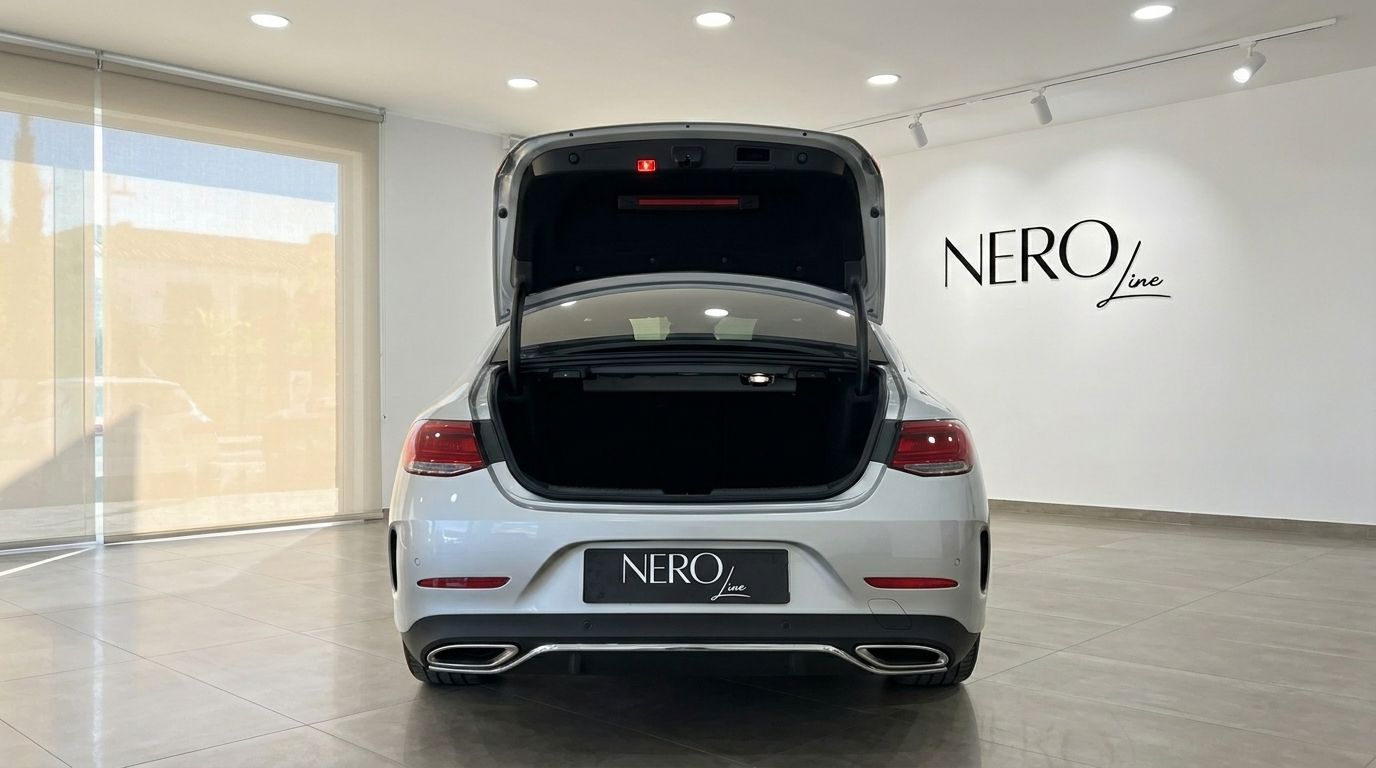 The silver Mercedes-Benz CLS 450 4MATIC is shown from the rear with its trunk open, revealing ample cargo space in an Alicante showroom.