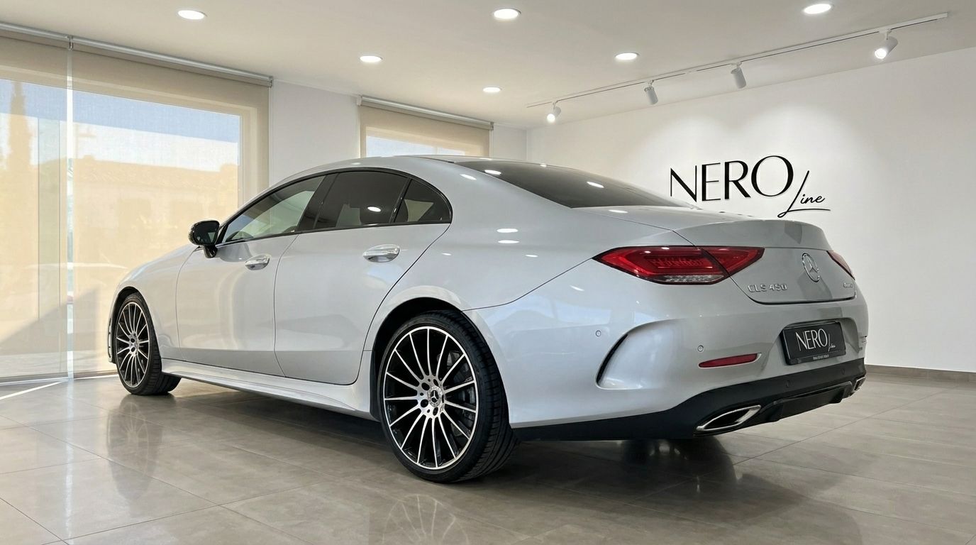 The silver Mercedes-Benz CLS 450 4MATIC luxury sedan is shown from a rear three-quarter angle in a showroom in Alicante.