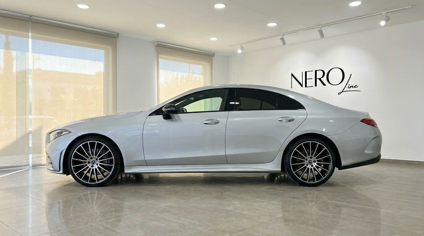 A sleek silver Mercedes-Benz CLS 450 4MATIC luxury sedan is shown from its elegant side profile in an Alicante showroom.