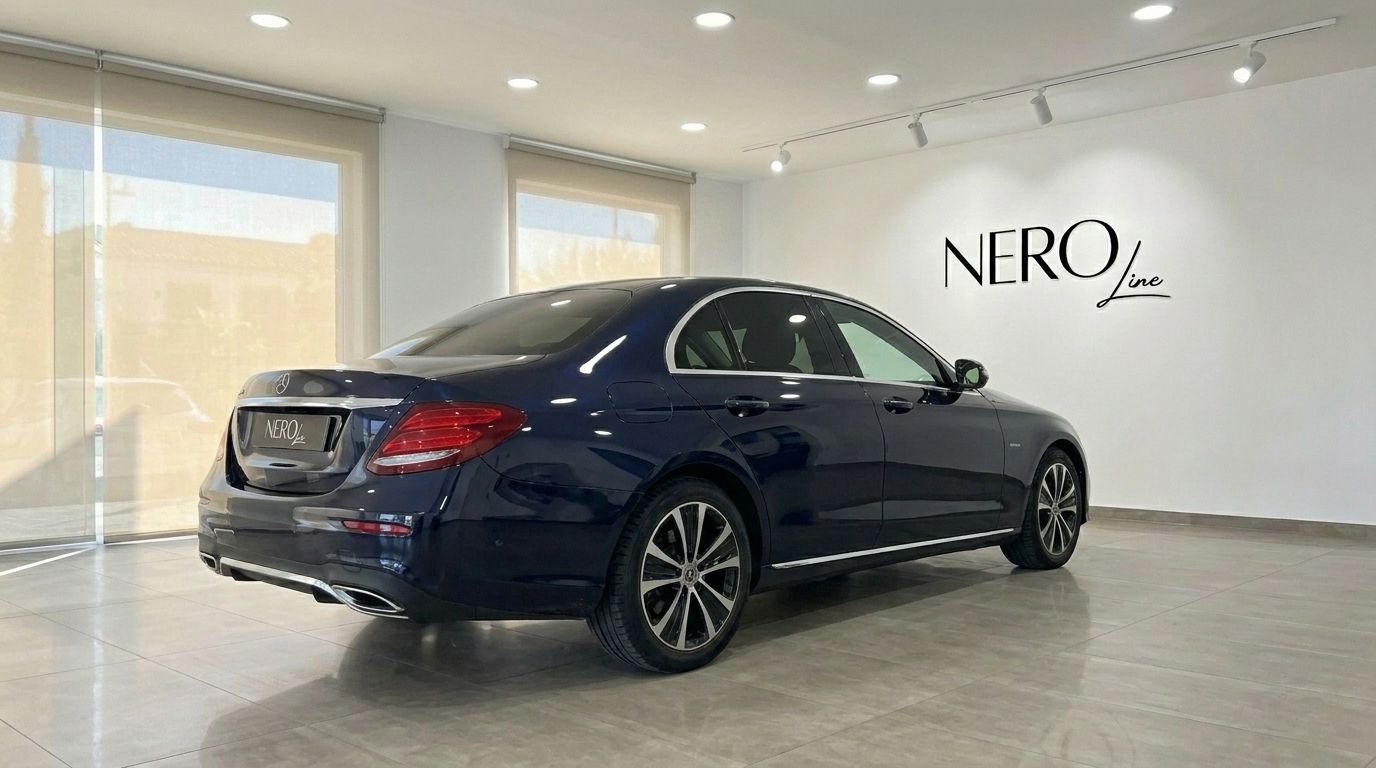 Dark blue Mercedes-Benz E 300de EQ Power sedan from a rear three-quarter view in a showroom in Alicante.