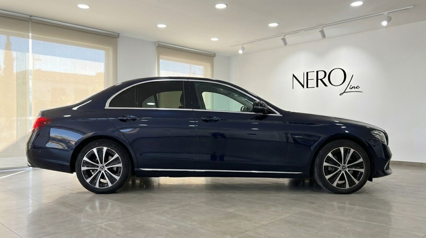 The dark blue Mercedes-Benz E 300de EQ Power sedan is showcased from its side profile in a modern Alicante showroom.