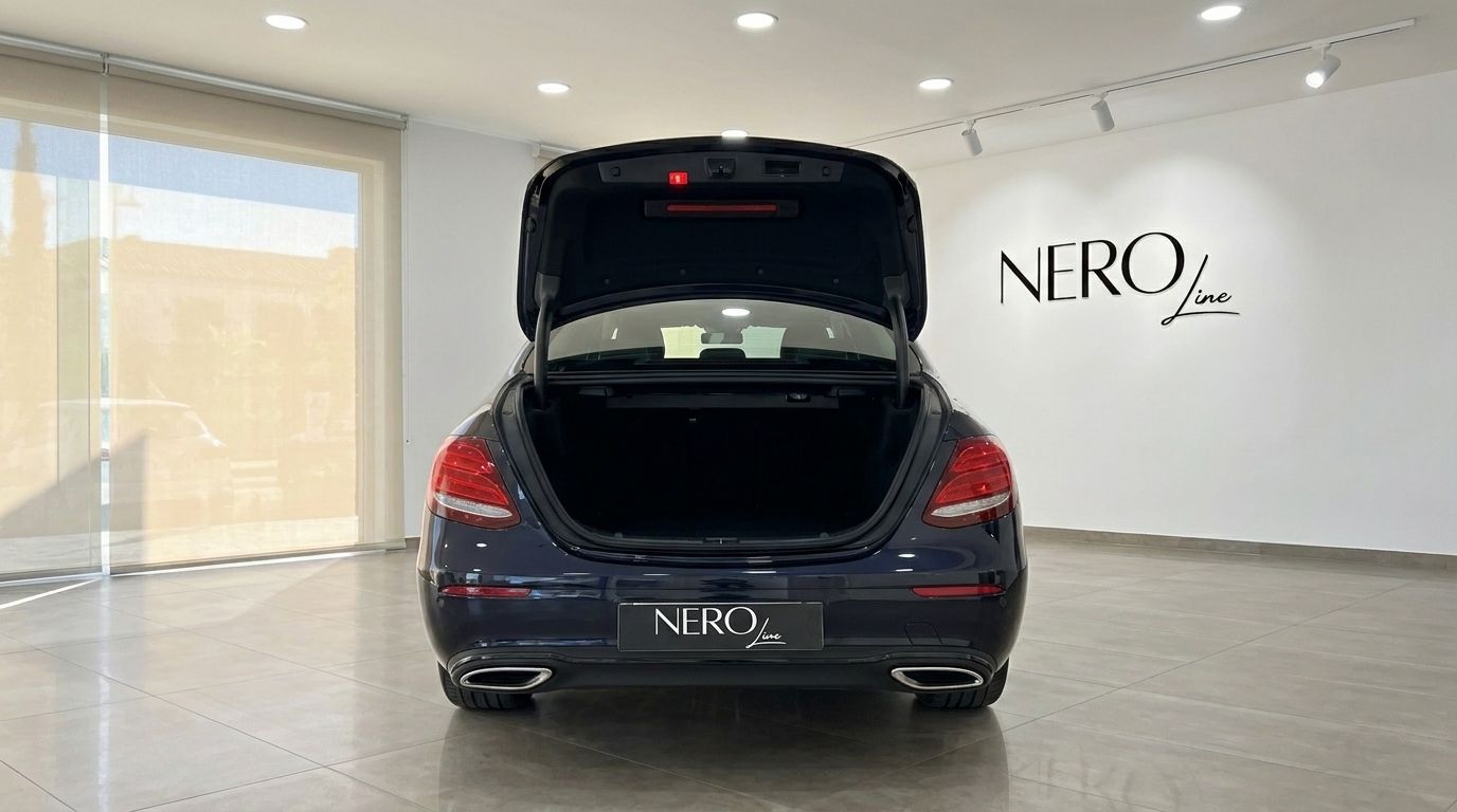 Rear view of a dark blue Mercedes-Benz E 300de EQ Power with its trunk open, parked in a showroom in Alicante.