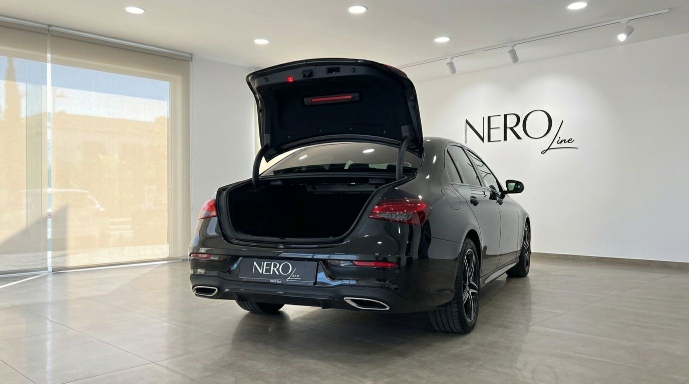 The black Mercedes-Benz E 300de is shown from the rear with its trunk open, parked in a showroom in Barcelona.