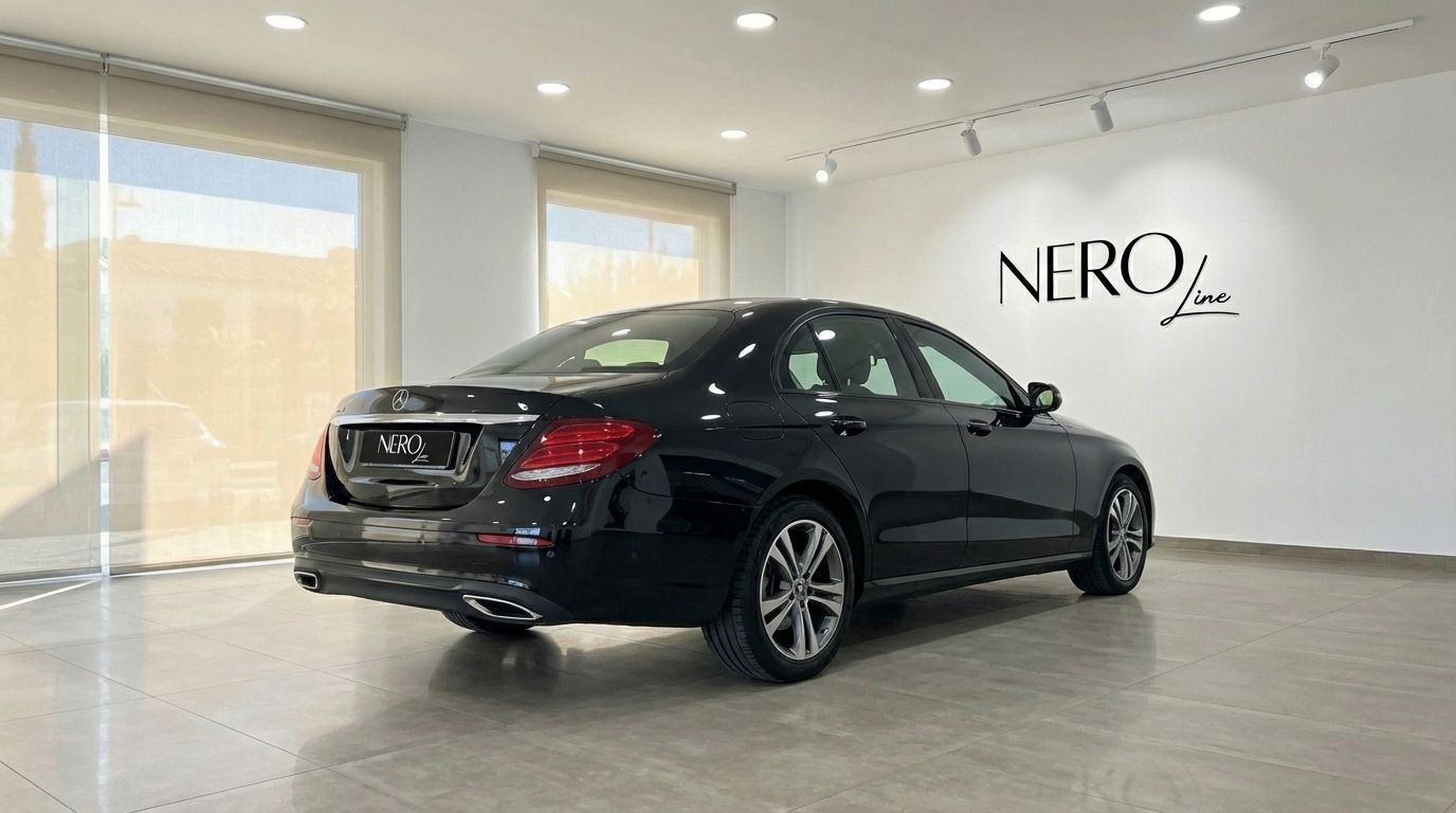 A sleek black Mercedes-Benz E 300de sedan is parked in a showroom in Barcelona, viewed from its rear three-quarter angle.
