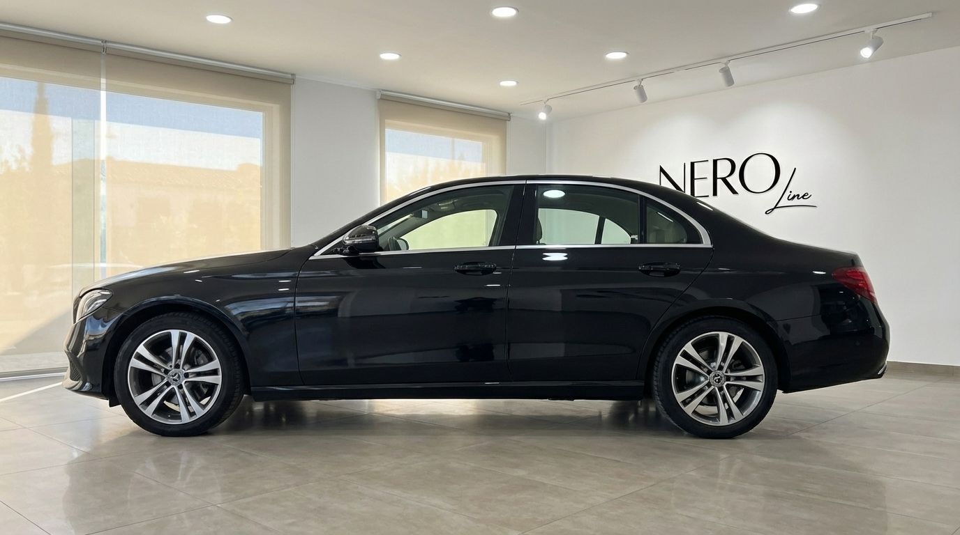 The sleek black Mercedes-Benz E 300de luxury sedan is shown in a full side profile view inside a bright showroom in Barcelona.