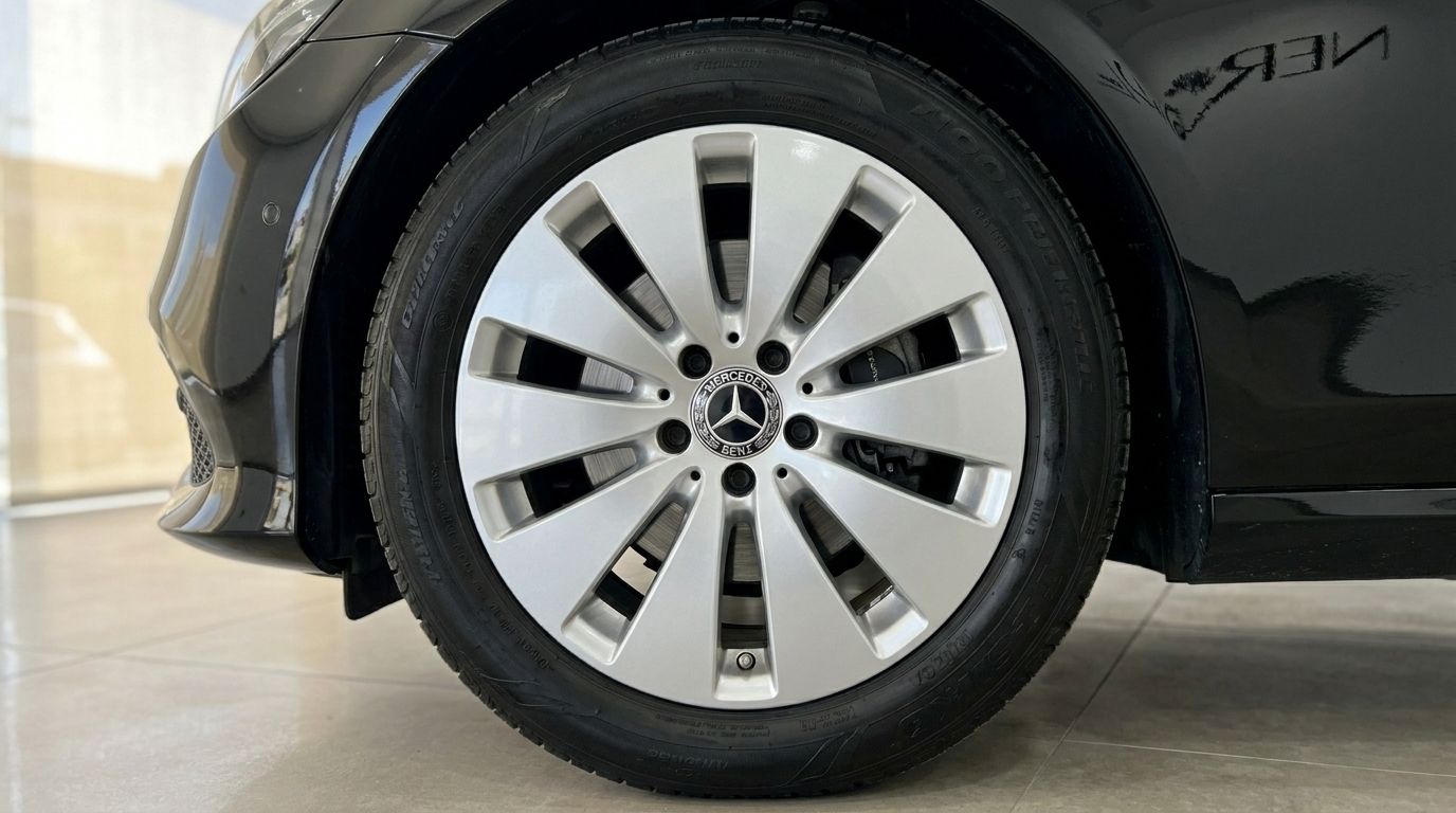 A close-up view of the Mercedes-Benz E-Class's front wheel with silver multi-spoke rim and black tire in Alicante.