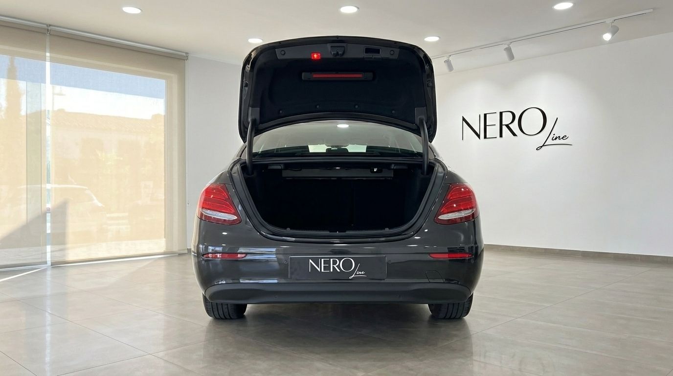 The rear view of a black Mercedes-Benz E-Class with its trunk open, displayed in a luxury showroom in Alicante.
