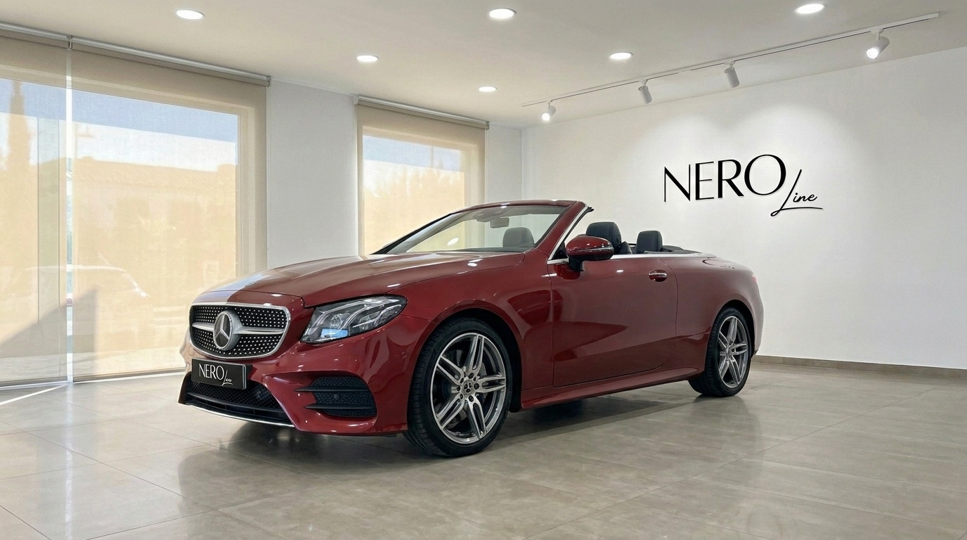 Mercedes-Benz E-Class Cabrio AMG Line — Mallorca A burgundy red Mercedes-Benz E-Class Cabrio AMG Line convertible is parked in a showroom in Mallorca, showcasing its sleek design.