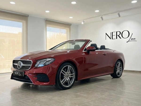 Mercedes-Benz Clase E Cabrio AMG Line — Mallorca Un Mercedes-Benz Clase E Cabrio AMG Line rojo burdeos descapotable está aparcado en un concesionario en Mallorca, mostrando su elegante diseño.