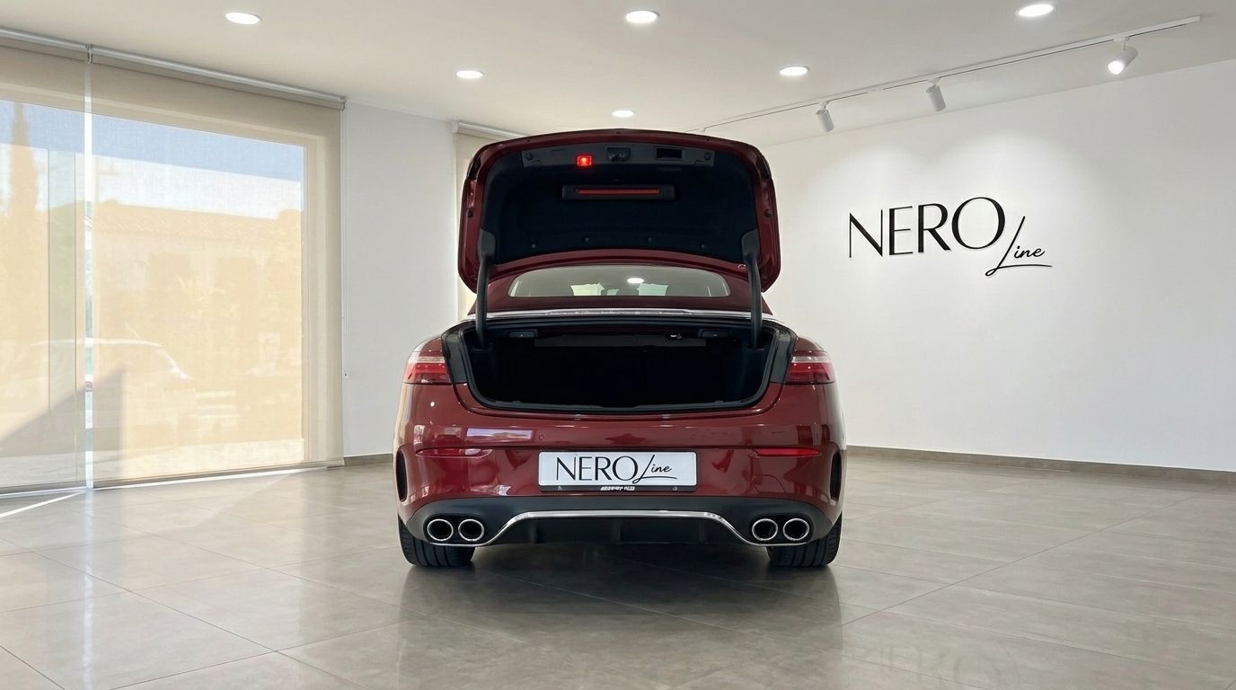 The burgundy red Mercedes-Benz E-Class Cabrio AMG Line is shown from the rear with its trunk open, in a showroom in Mallorca.