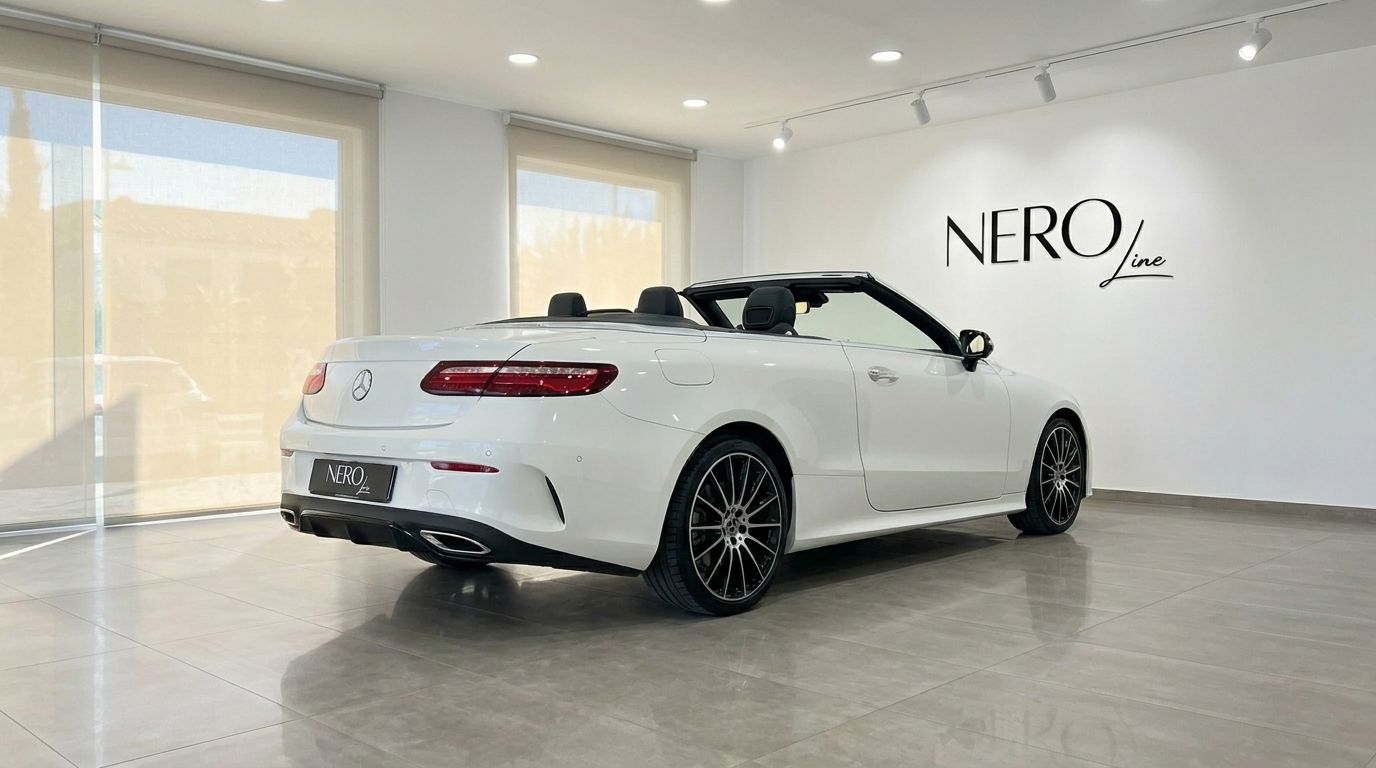 La Mercedes-Benz E200 Cabrio blanche, décapotée, est présentée sous un angle arrière trois quarts dans un showroom à Marbella.
