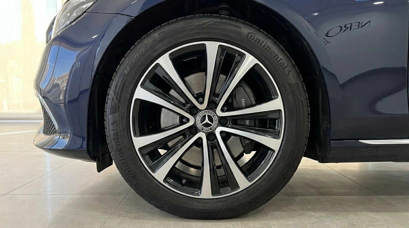 Close-up of the front wheel and dark blue body of the Mercedes-Benz E 300de EQ Power, featuring multi-spoke alloy rims and Continental tires in Alicante.