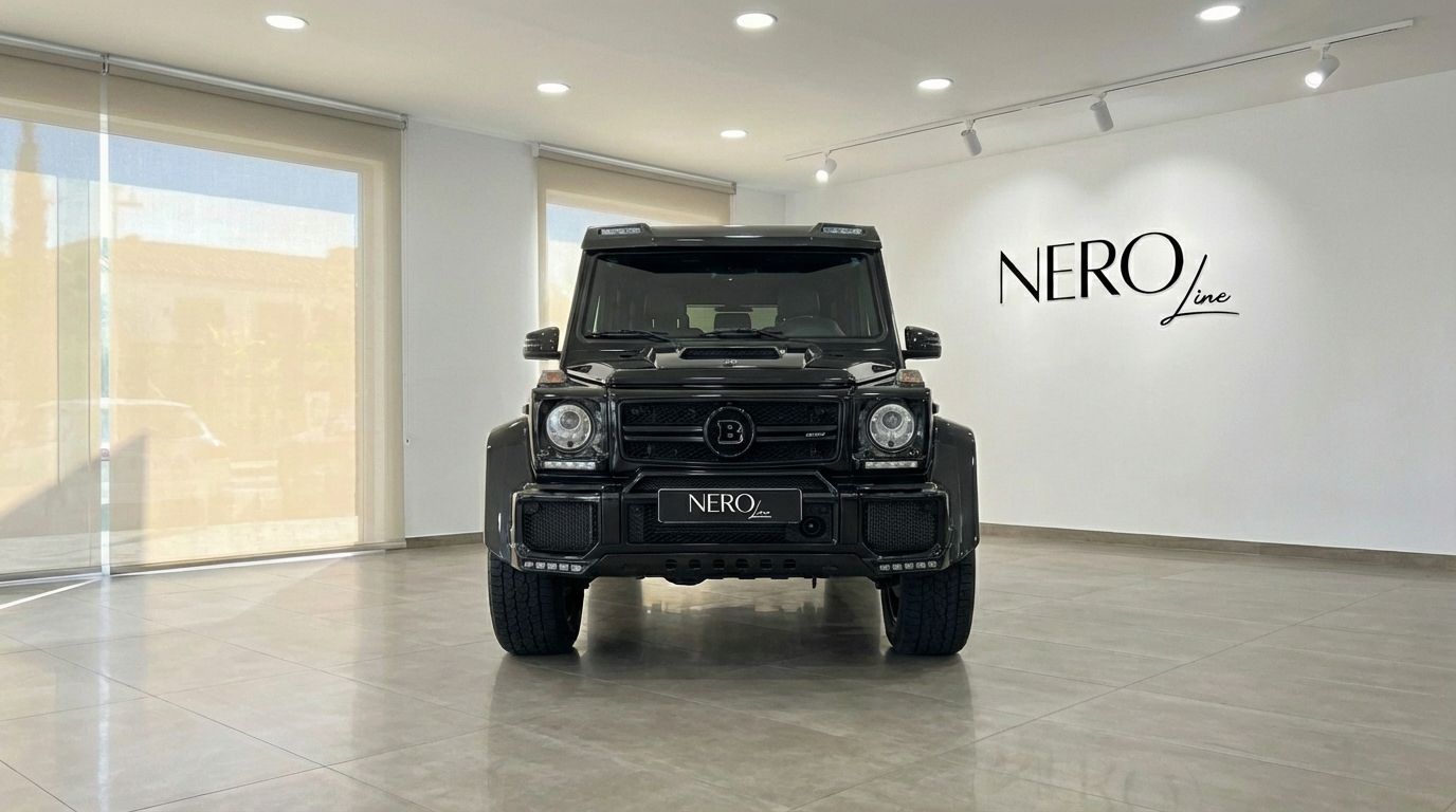 A black Mercedes-Benz G 500, possibly Brabus modified, is prominently displayed from the front in a modern showroom in Marbella.