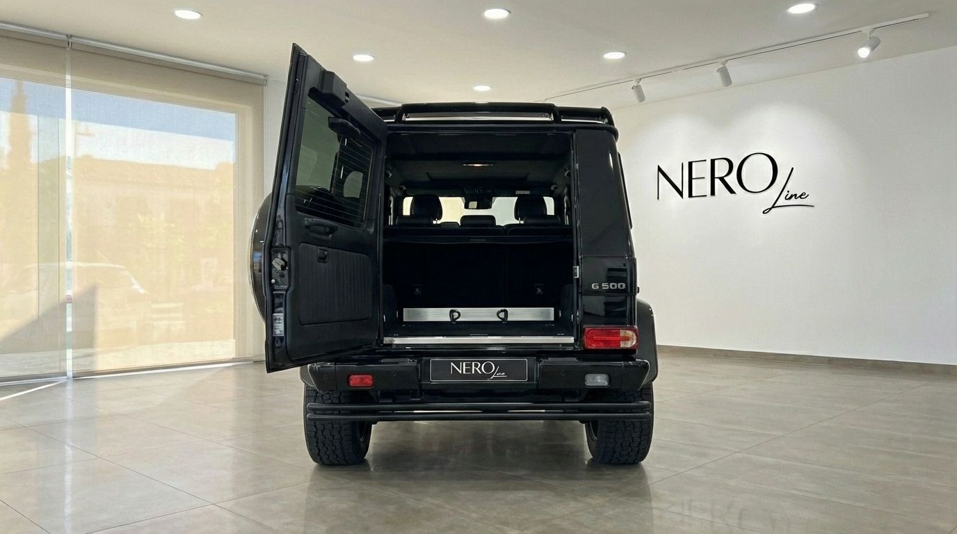 The rear view of a black Mercedes-Benz G 500 with its trunk open, showcasing the spacious cargo area in Marbella.