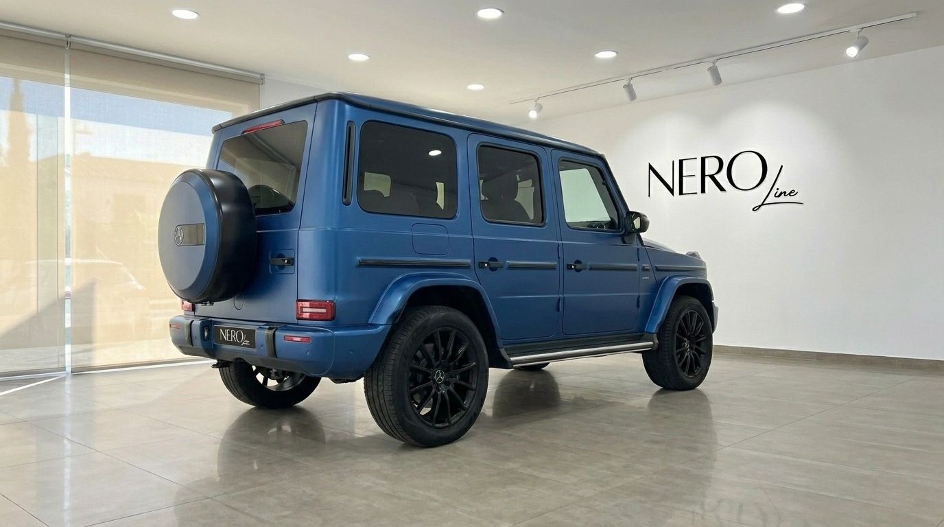 The matte dark blue Mercedes-Benz G 580 EQ is showcased from a rear three-quarter angle inside a modern showroom in Mallorca.