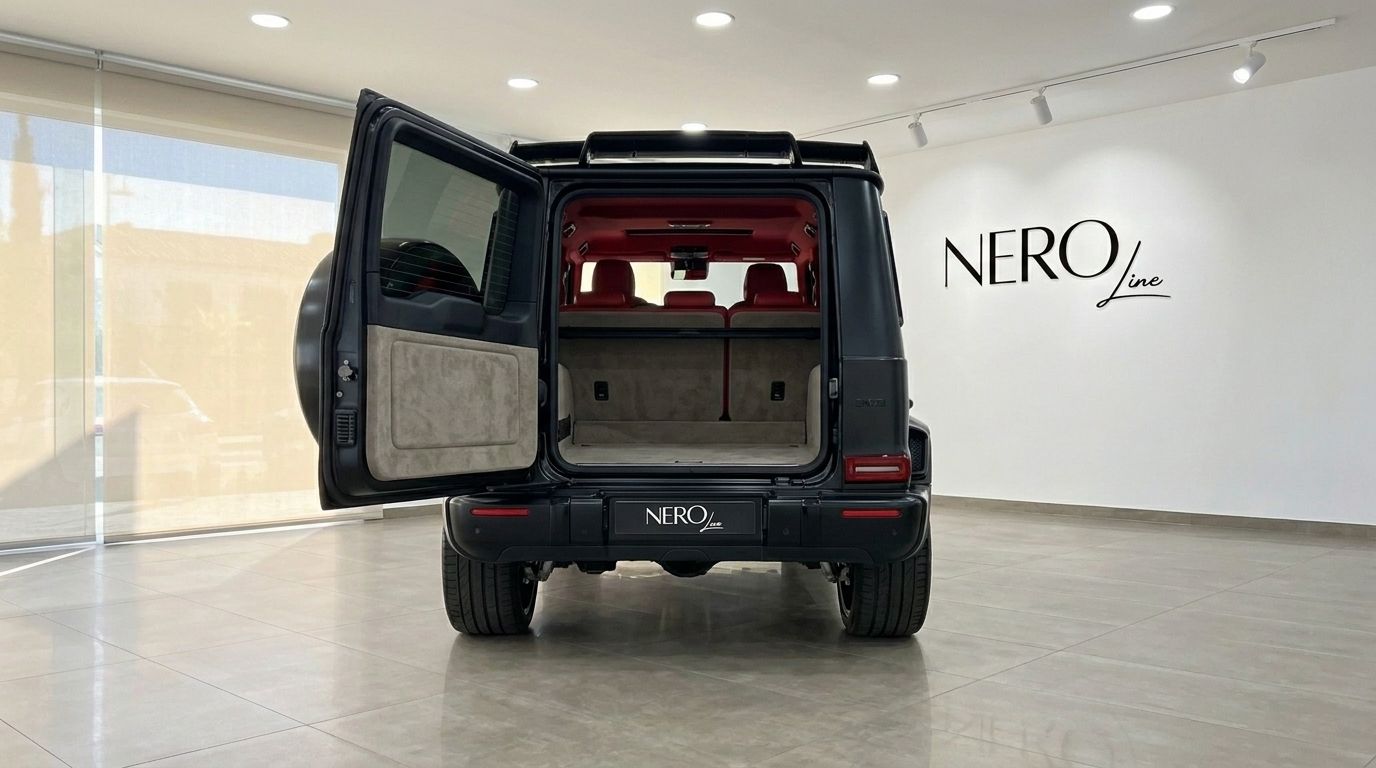 The matte black Mercedes-Benz G63 800 BRABUS from the rear, with its trunk open revealing the luxurious red interior and spacious cargo area in Ibiza.