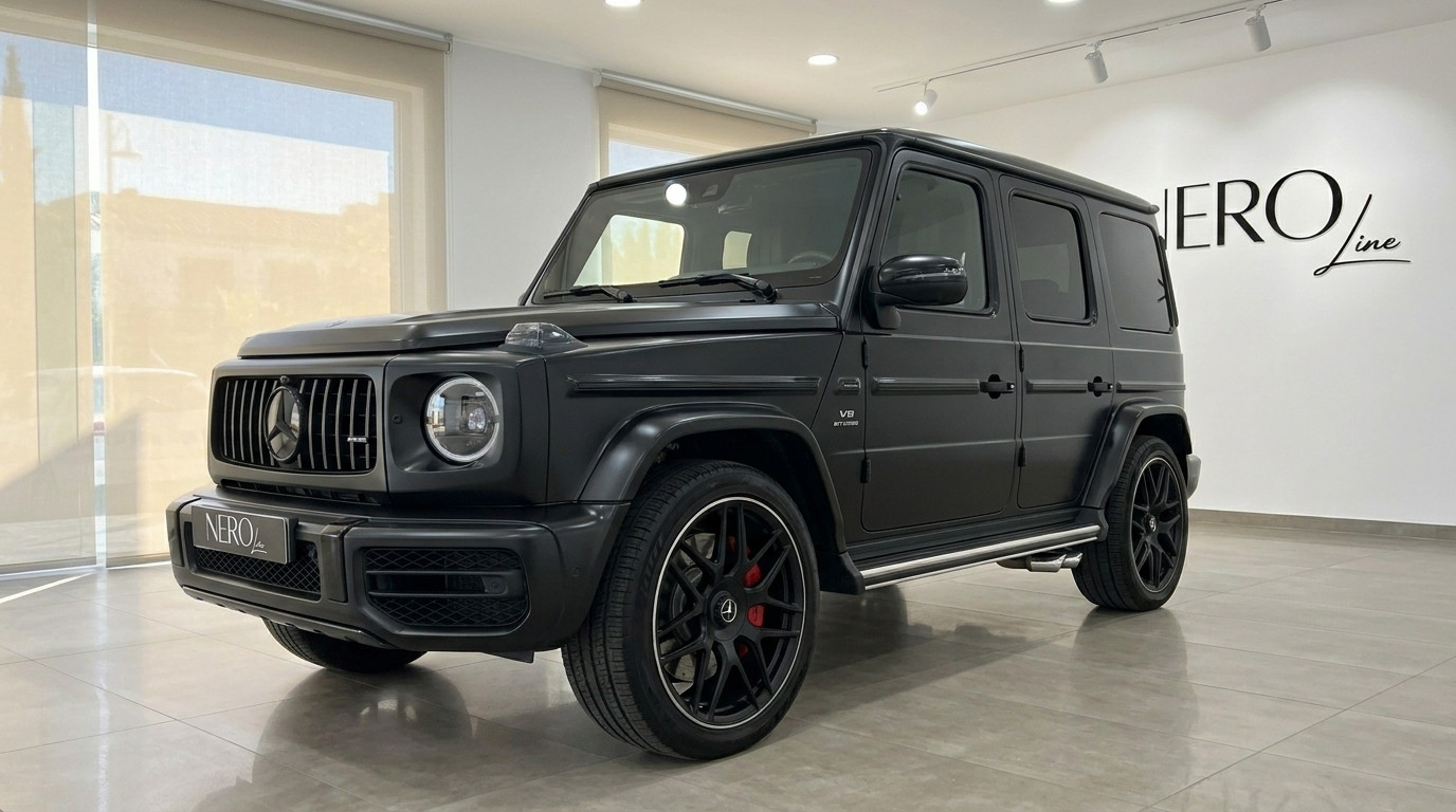 Mercedes-Benz G63 AMG — Vue avant en showroom Le Mercedes-Benz G63 AMG noir mat est présenté de trois quarts avant dans un showroom à Marbella.