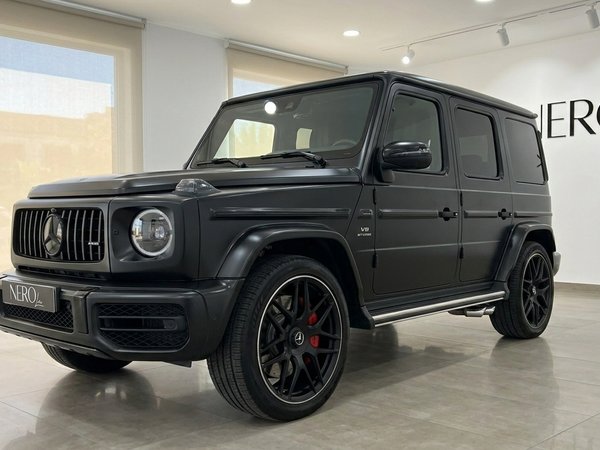 Mercedes-Benz G63 AMG — Vue avant en showroom Le Mercedes-Benz G63 AMG noir mat est présenté de trois quarts avant dans un showroom à Marbella.