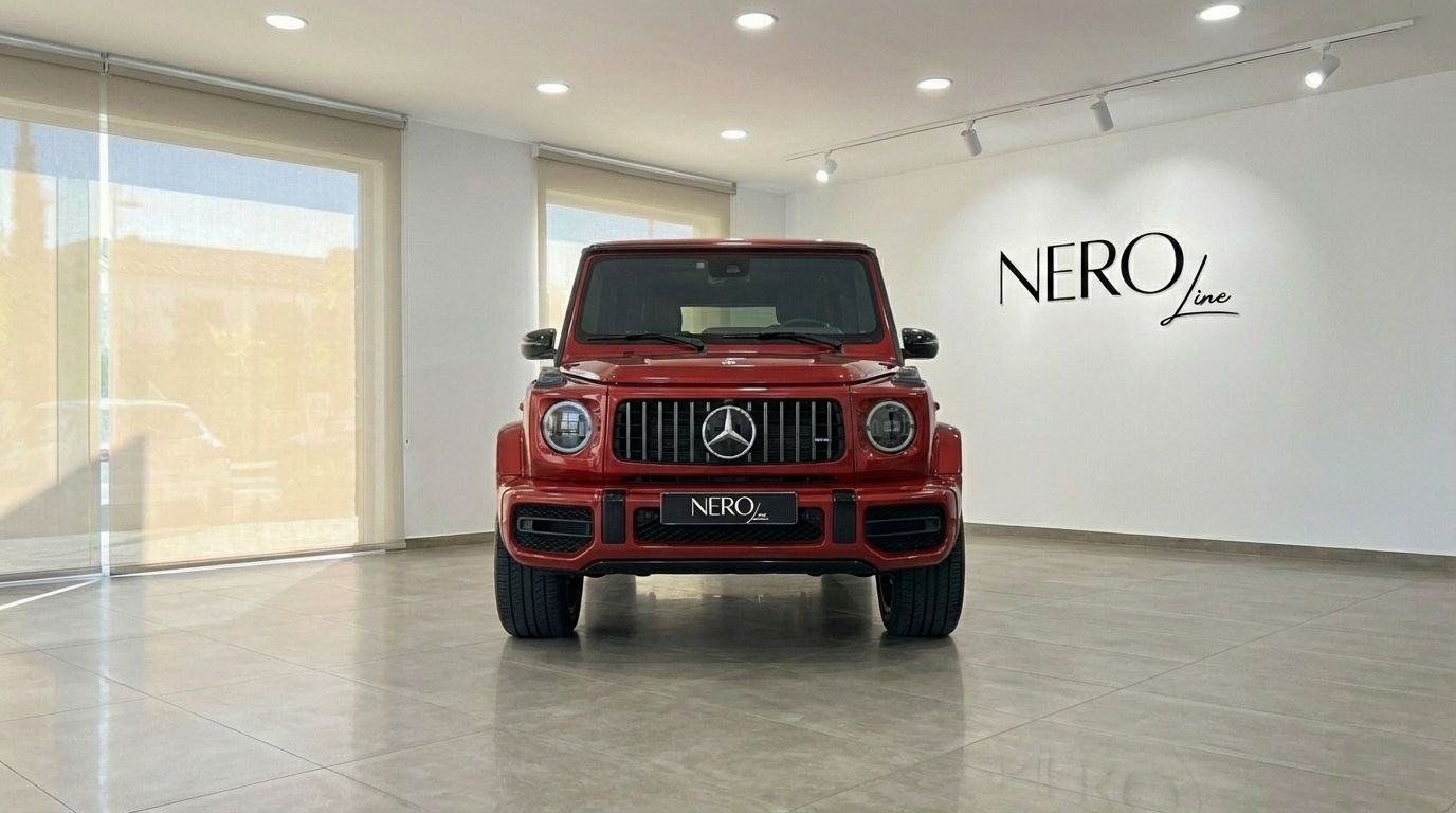 The glossy red Mercedes-Benz G63 AMG is showcased from the front view, parked inside a modern showroom in Alicante.